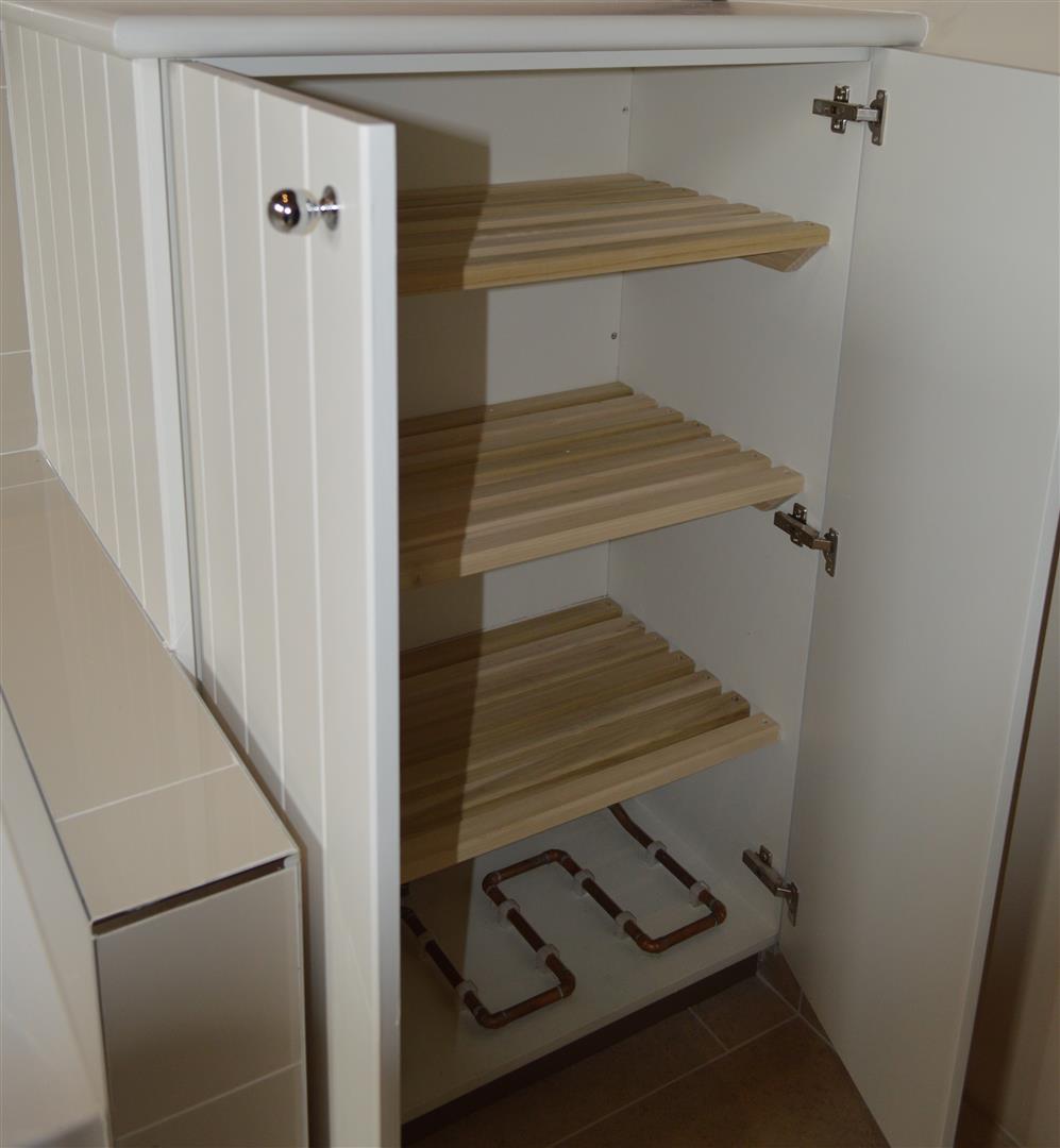 Air cupboard for drying out clothes and towels with untreated slats of wood.